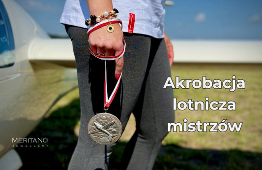 Część sylwetki kobiecej z medalem lotniczym w dłoci i bransoletką na tle szybowca Część sylwetki kobiecej z medalem lotniczym w dłoci i bransoletką na tle szybowca