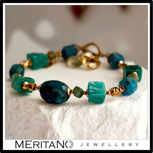 Bransoletka z kamieni naturalnych amazonitu i apatytu leżąca na białym kamieniu Bransoletka z kamieni naturalnych amazonitu i apatytu leżąca na białym kamieniu