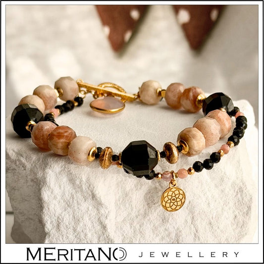 Bransoletka z czarnym turmalinem i różowym kamieniem słonecznym, podwójna z zawieszką, leżąca na białym gipsie Bransoletka z czarnym turmalinem i różowym kamieniem słonecznym, podwójna z zawieszką, leżąca na białym gipsie