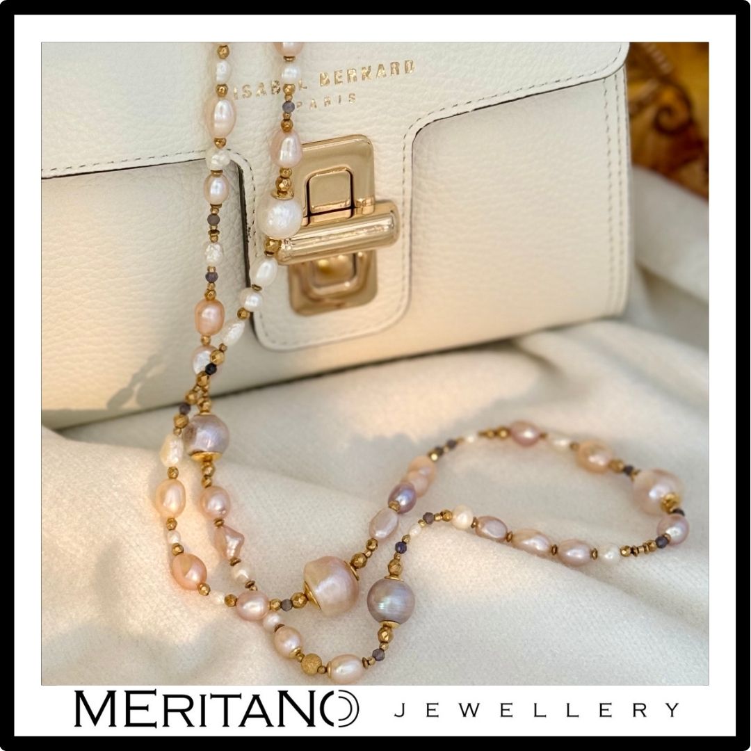 Długi naszyjnik z pereł naturalnych przy jasnej torebce