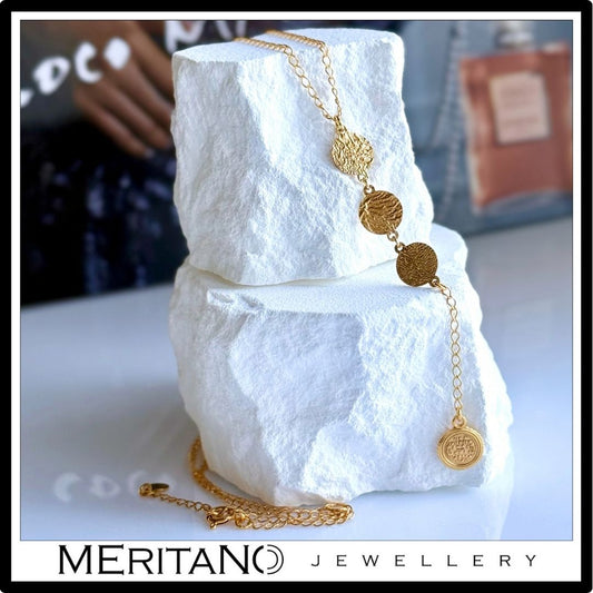 Łańcuszek krawatka ze złotymi monetkami - widok na białym kamieniu. Łańcuszek krawatka ze złotymi monetkami - widok na białym kamieniu.