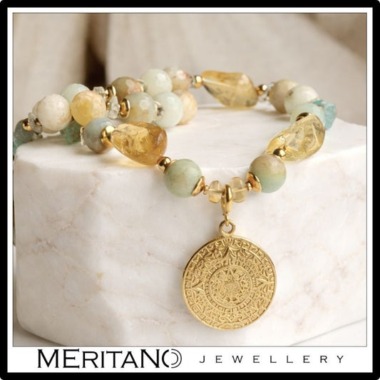 Naszyjnik z amazonitem, cytrynem i apatytem ze złota zawieszką leżący na bloku marmuru Naszyjnik z amazonitem, cytrynem i apatytem ze złota zawieszką leżący na bloku marmuru