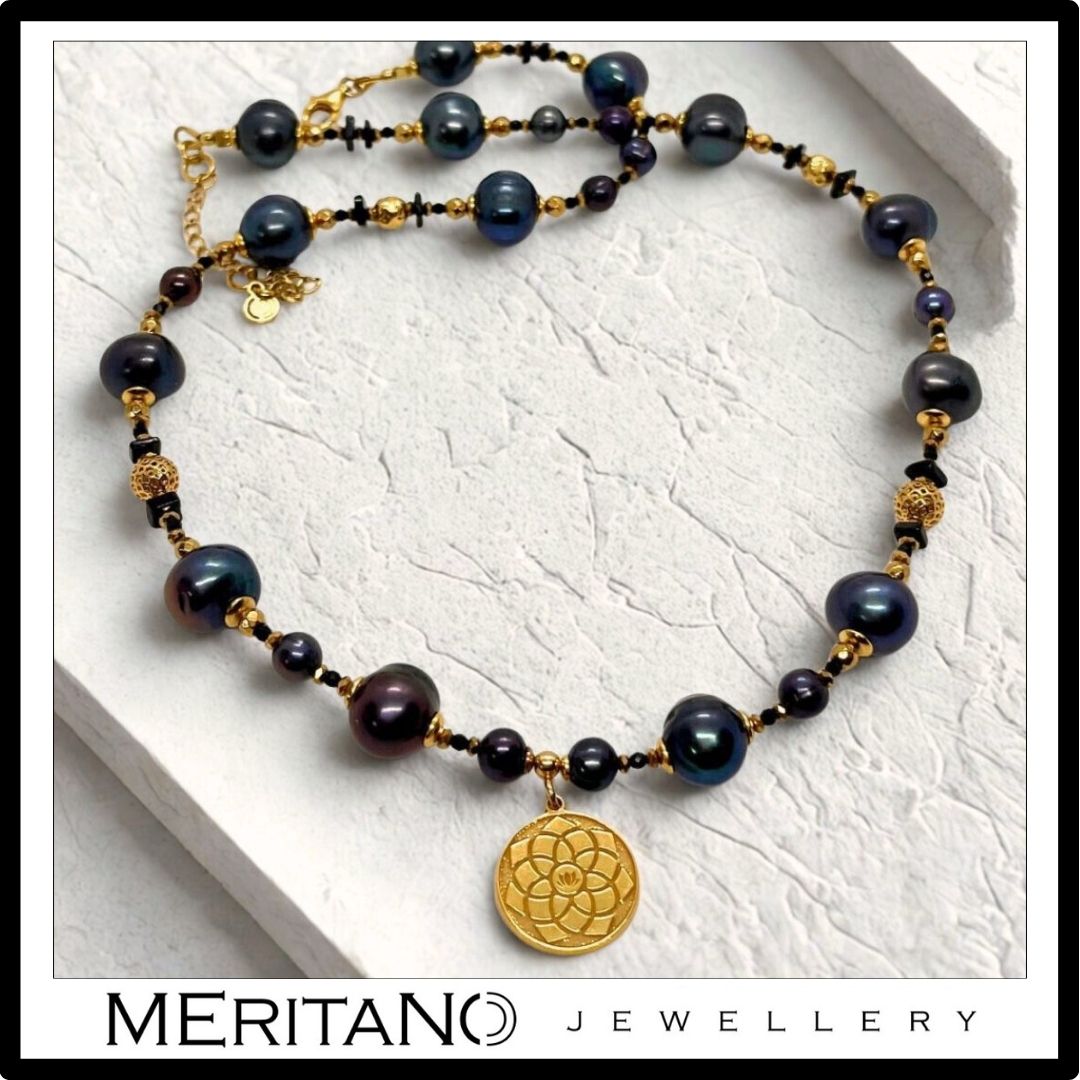 Naszyjnik z czarnych pereł naturalnych ze złotą zawieszką na gipsowej powierzchni