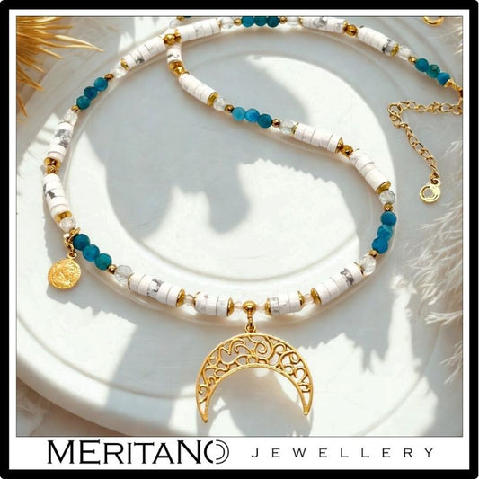 Biały naszyjnik z howlitem, apatytem i złotym księżycem. widok na białej tacy. Biały naszyjnik z howlitem, apatytem i złotym księżycem. widok na białej tacy.