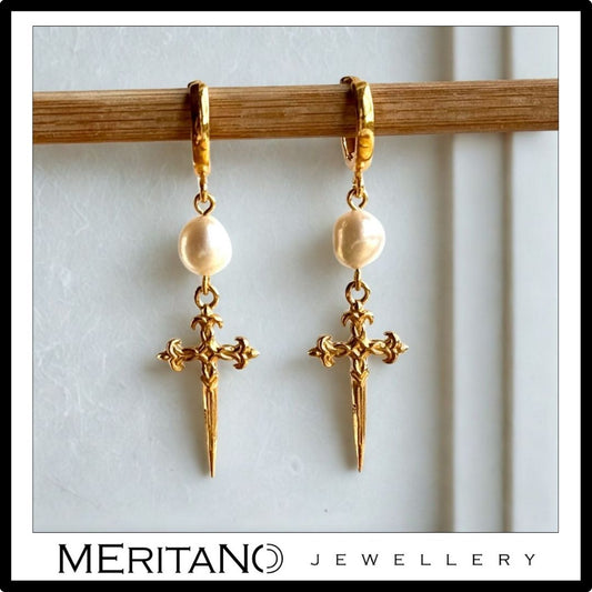 Wiszące kolczyki z perłami i złotymi sztyletami. Widok z przodu. Wiszące kolczyki z perłami i złotymi sztyletami. Widok z przodu.