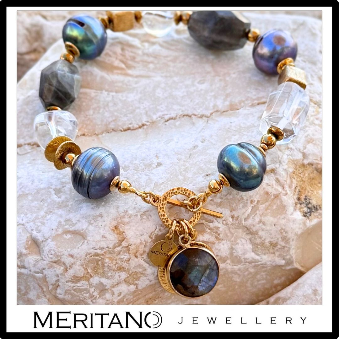 Bransoletka z zielonymi perłami barokowymi, labradorytem i kryształem górskim, wykończona złotą monetą i zawieszką z labradorytem, prezentowana na tle jasnego kamienia | Meritano Jewellery