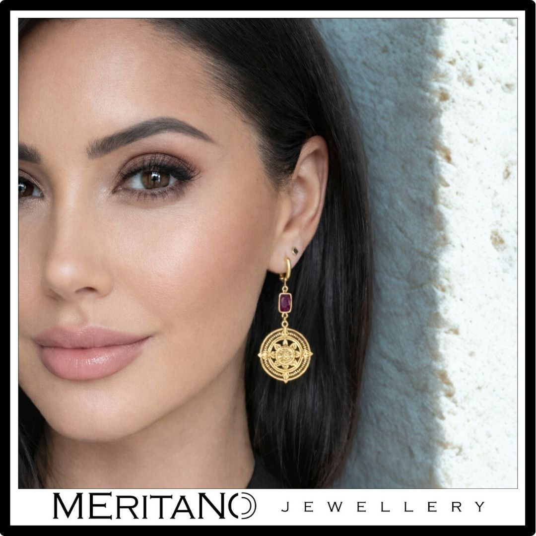 Złote kolczyki z granatem i symbolem Majów widoczne na uchu z proporcją