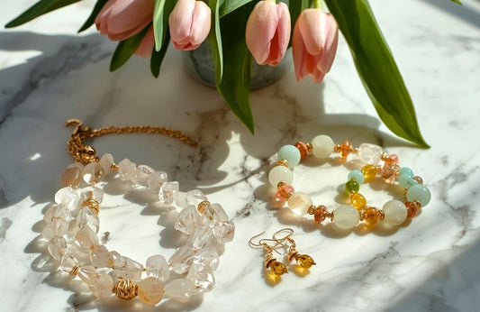 Lekka biżuteria na wiosnę z pastelowych i zielonych kamieni naturalnych w jasnym świetle z tulipanami w tle