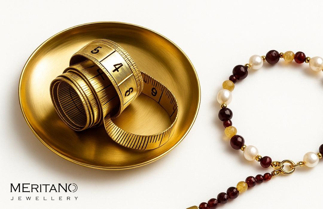 miarka krawiecka leżąca na złotym talerzu a obok bransoletka z kamieni naturalnych i pereł.