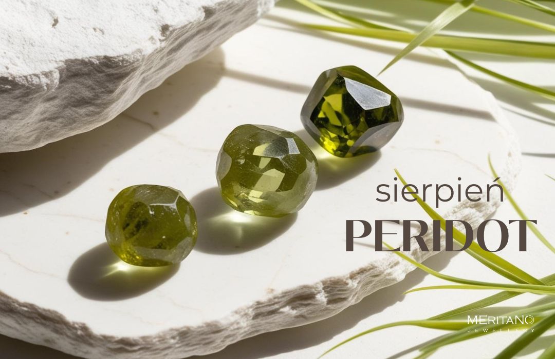 Peridot leżący na białym kamieniu, obok liście trawy