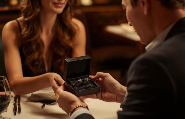 Para w restauracji - kobieta wręcza meżczyżnie w prezencie bransoletkę z kamieni naturalnych