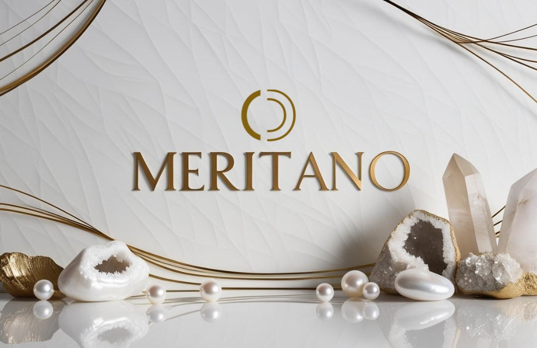 Złoty napis Meritano na białym tle. U dołu kamienie naturalne.