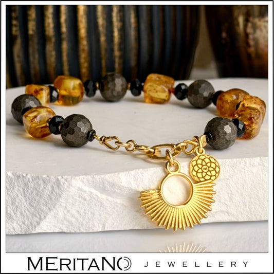 Bransoletka z bursztynem i pirytem ze złotą zawieszką na białym gipsie