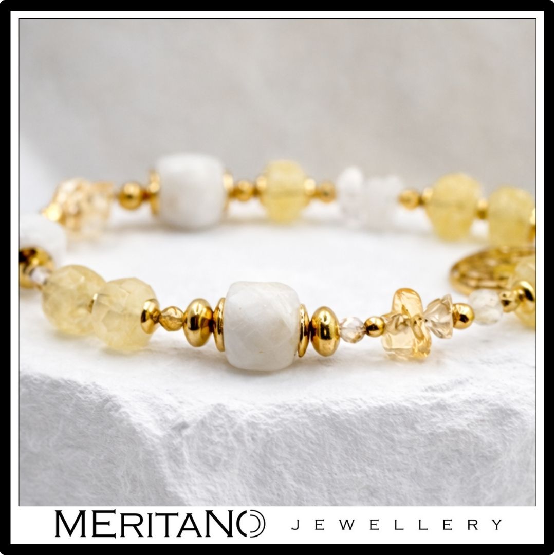 Bransoletka z kamieniem księżycowym i cytrynem, ozdobiona zawieszką, leżąca na kamieniu  - zbliżenie