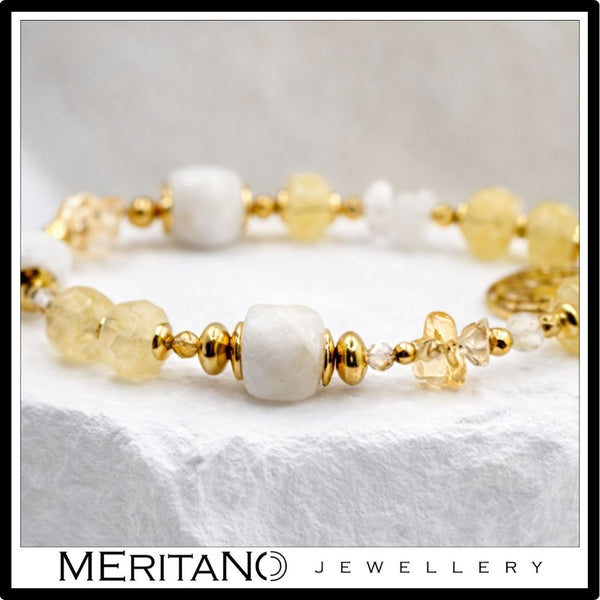 Bransoletka z kamieniem księżycowym i cytrynem, ozdobiona zawieszką, leżąca na kamieniu  - zbliżenie