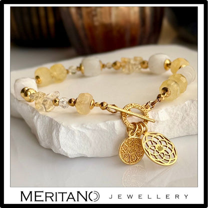 Bransoletka z kamieniem księżycowym i cytrynem, ozdobiona zawieszką, leżąca na kamieniu - biżuteria Meritano Jewellery
