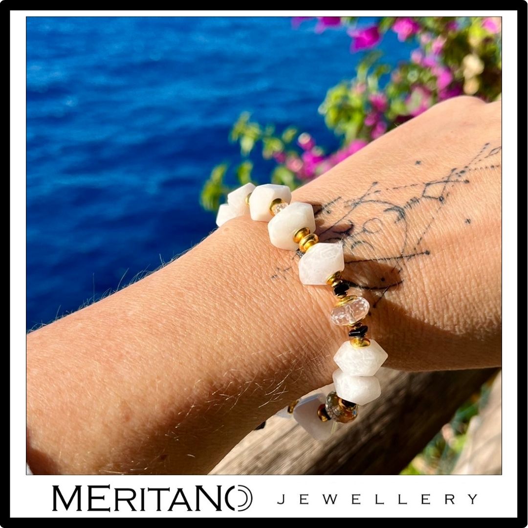 Bransoletka z kamieniem księżycowym i kryształem górskim na ręce na tle morza