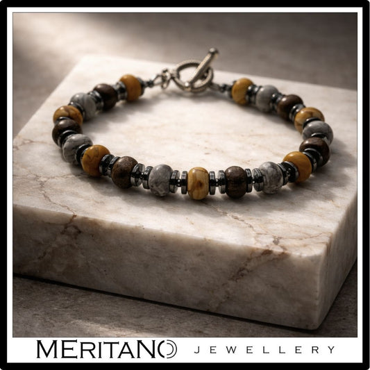 Bransoletka męska z bronzytem i jaspisem leżąca na bloku marmurowym