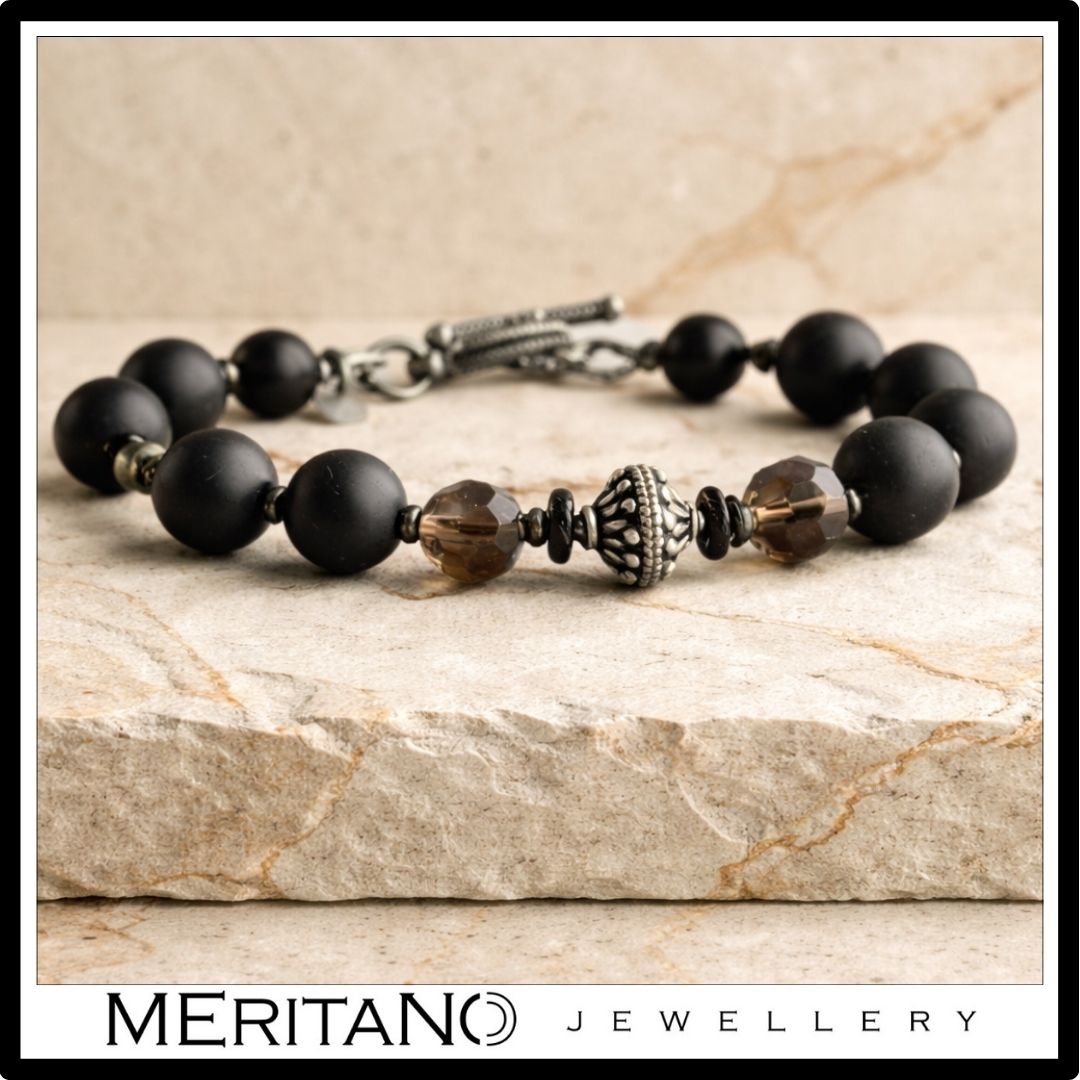 Bransoletka męska z czarnym turmalinem i kwarcem dymnym leżąca na jasnym piaskowcu