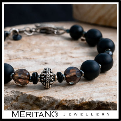 Bransoletka męska z czarnym turmalinem i kwarcem dymnym leżąca na jasnym kamieniu