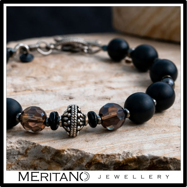 Bransoletka męska z czarnym turmalinem i kwarcem dymnym leżąca na jasnym kamieniu