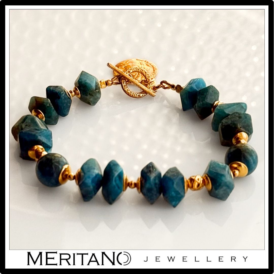 Bransoletka z niebieskim kamieniem apatyt i złotą zawieszką na jasnym tle