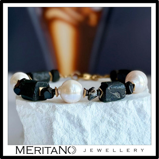 Bransoletka z perłami naturalnymi barokowymi i czarnym turmalinem leżąca na białym kamieniu Bransoletka z perłami naturalnymi barokowymi i czarnym turmalinem leżąca na białym kamieniu