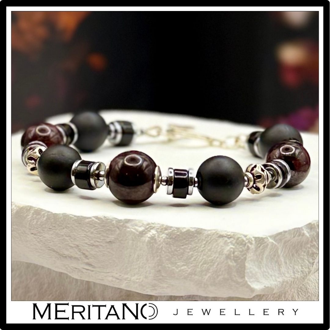 Bransoletka z turmalinem i granatem z dodatkami ze srebra, leżąca na białym kamieniu