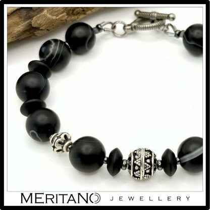 Bransoletka z kamieni naturalnych onyks i agat obok drewna