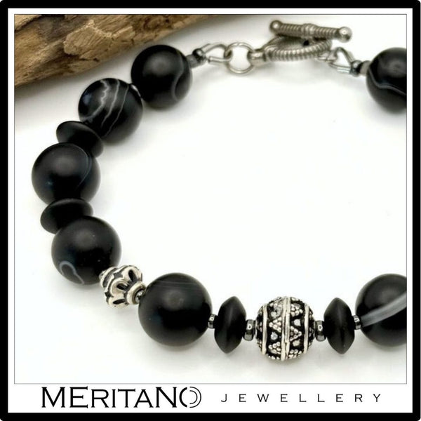 Bransoletka z kamieni naturalnych onyks i agat obok drewna