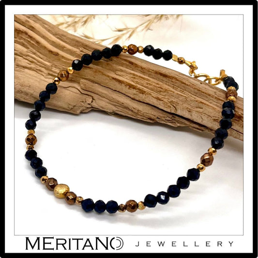 cienka czarna bransoletka z kamieni naturalnych z turmalinem, leżąca obok drewna