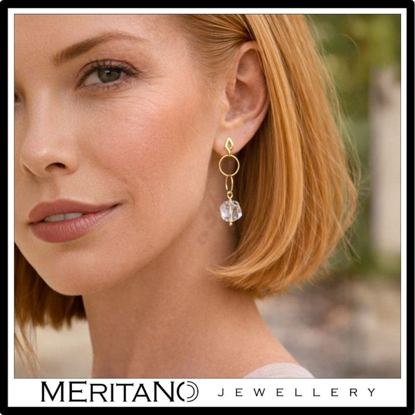 Złote kolczyki koła z kryształem górskim na uchu modelki z proporcją wielkości