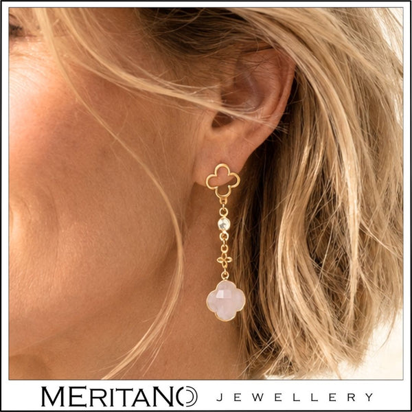Wiszące kolczyki z różowym kamieniem na uchu modelki w zbliżeniu