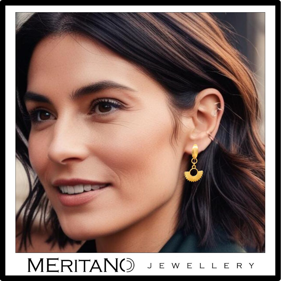 złote wiszące kolczyki słońca na uchu