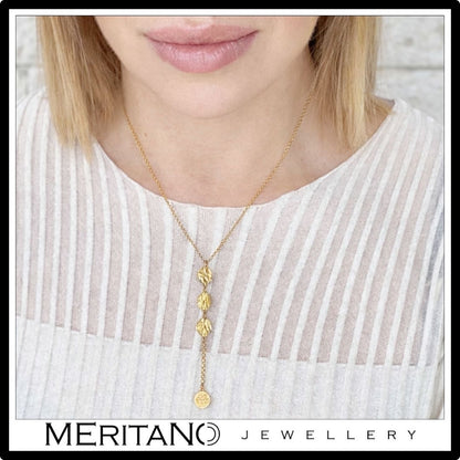 Złoty łańcuszek krawatka z monetami - widok na szyi modelki w białej bluzce