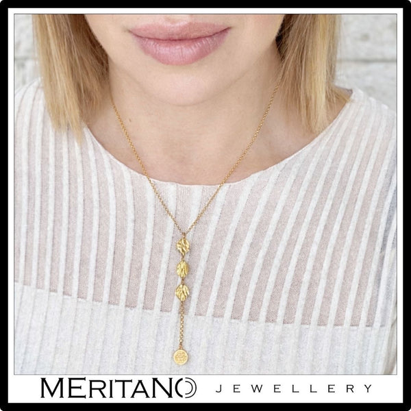 Złoty łańcuszek krawatka z monetami - widok na szyi modelki w białej bluzce