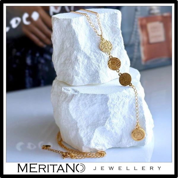 Łańcuszek krawatka ze złotymi monetkami - widok na białym kamieniu.