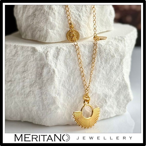 łańcuszek z zawieszkami ze srebra pozłacanego obok białego kamienia