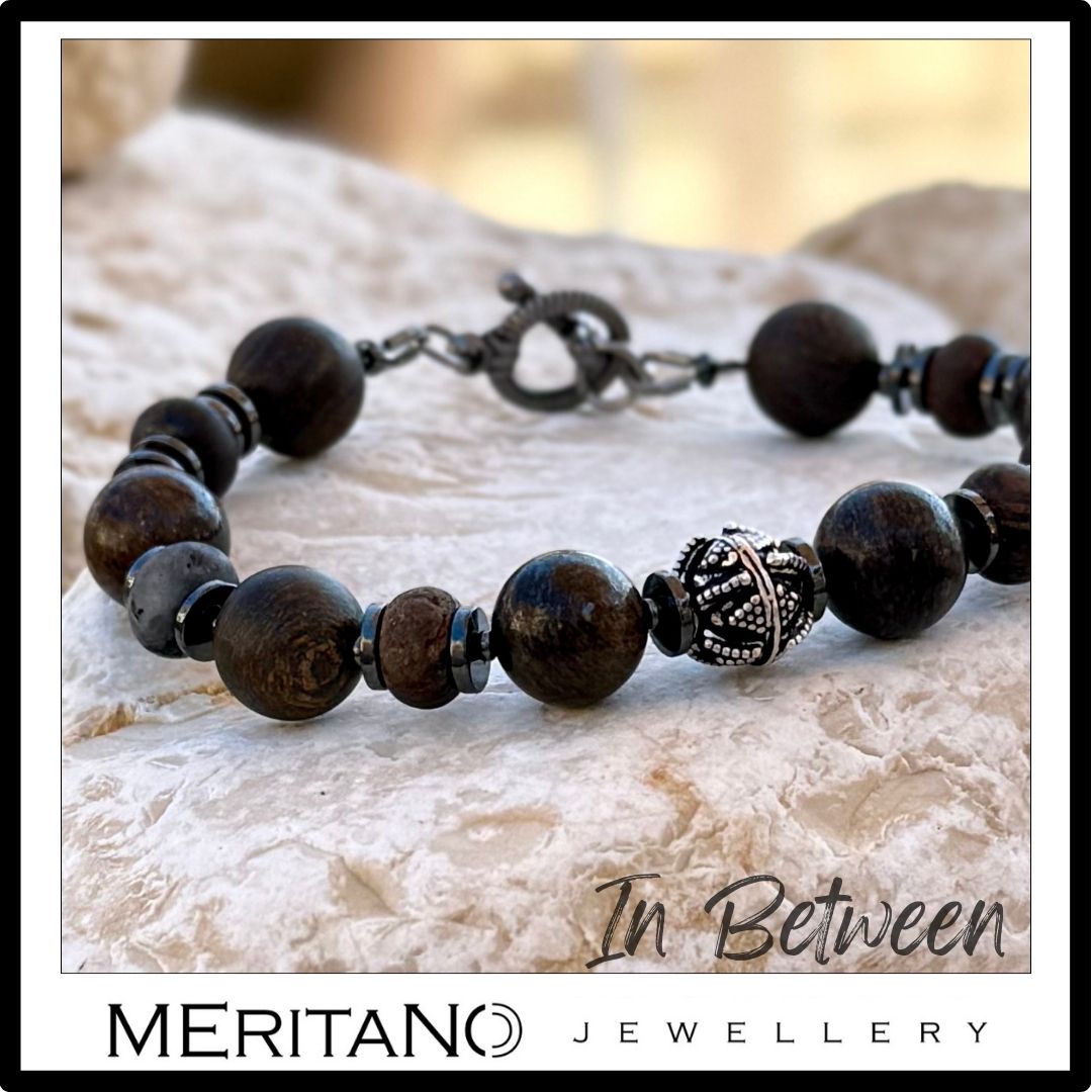 Brązowa bransoletka męska z kamieni bronzytu leżąca na kamieniu