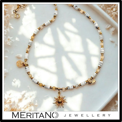 Naszyjnik howlit i cytryn ze złotą zawieszką słońce. Widok z góry.