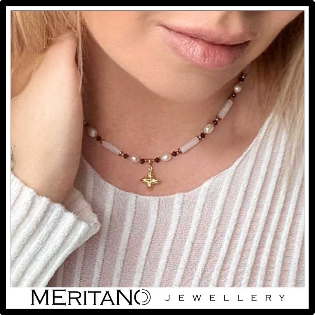 Naszyjnik z jadeitem, perłami i granatem, ze złotą zawieszką. Widok na szyi przy jasnej bluzce.