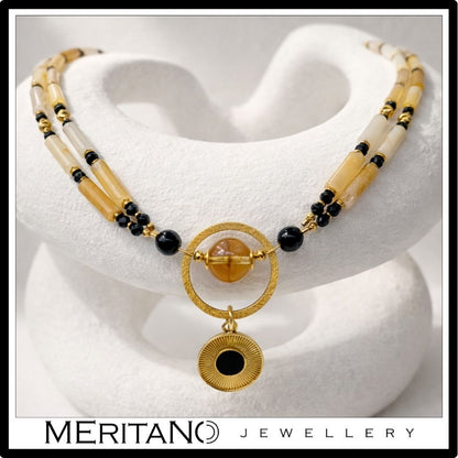 Naszyjnik z kwarcem, turmalinem i cytrynem z czarną złotą zawieszką leżący na kompozycji z gipsu