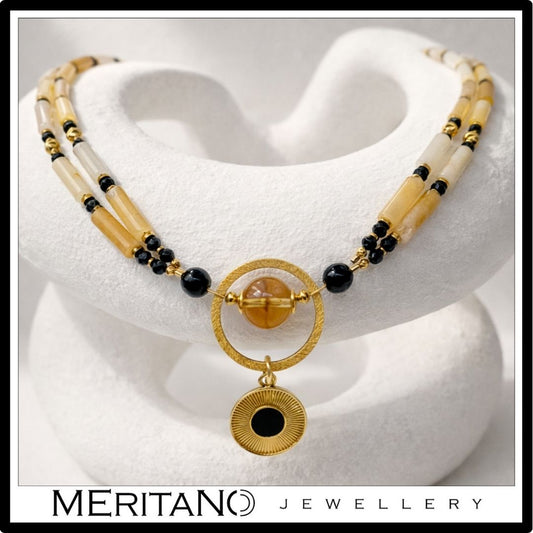 Naszyjnik z kwarcem, turmalinem i cytrynem z czarną złotą zawieszką leżący na kompozycji z gipsu