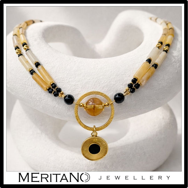 Naszyjnik z kwarcem, turmalinem i cytrynem z czarną złotą zawieszką leżący na kompozycji z gipsu