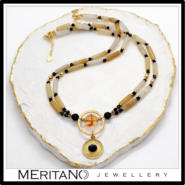 Naszyjnik z kwarcem, turmalinem i cytrynem z czarną złotą zawieszką leżący na białej tacy