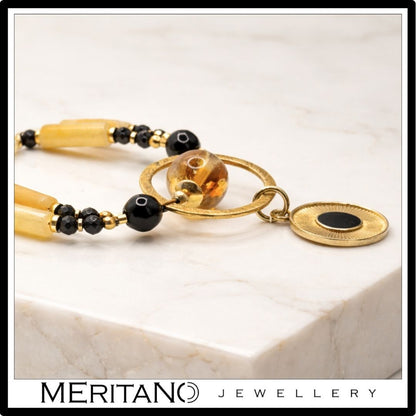 Naszyjnik z kwarcem, turmalinem i cytrynem z czarną złotą zawieszką leżący - skala kamieni