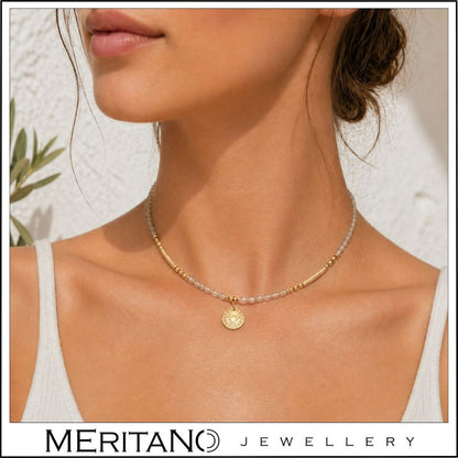 Naszyjnik z labradorytem i czakrą gardła na szyi modelki w białej stylizacji