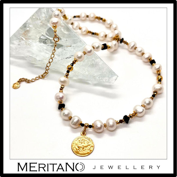 Naszyjnik z drobnych pereł naturalnych ze złotą zawieszką obok szkła