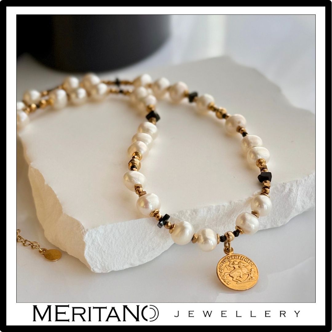 Naszyjnik z pereł naturalnych ze spinelem i złotą zawieszką leżący na białym kamieniu - biżuteria Meritano Jewellery