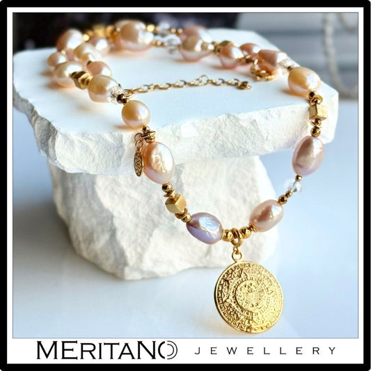 Różowe perły barokowe w naszyjniku ze złotą zawieszką. Widok na kamieniu.